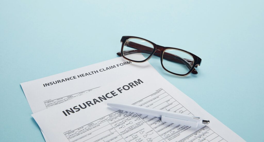close-up view of insurance form, insurance health claim form, eyeglasses and pen on blue